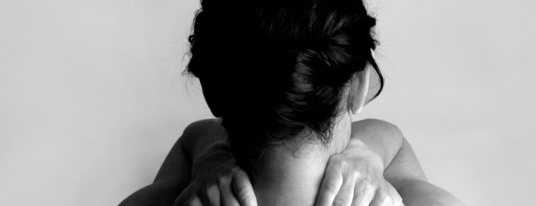 Nude woman with back pain on a gray background