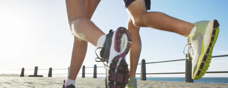 A cropped low-angle shot of a young couple running along the esplanade at sunset